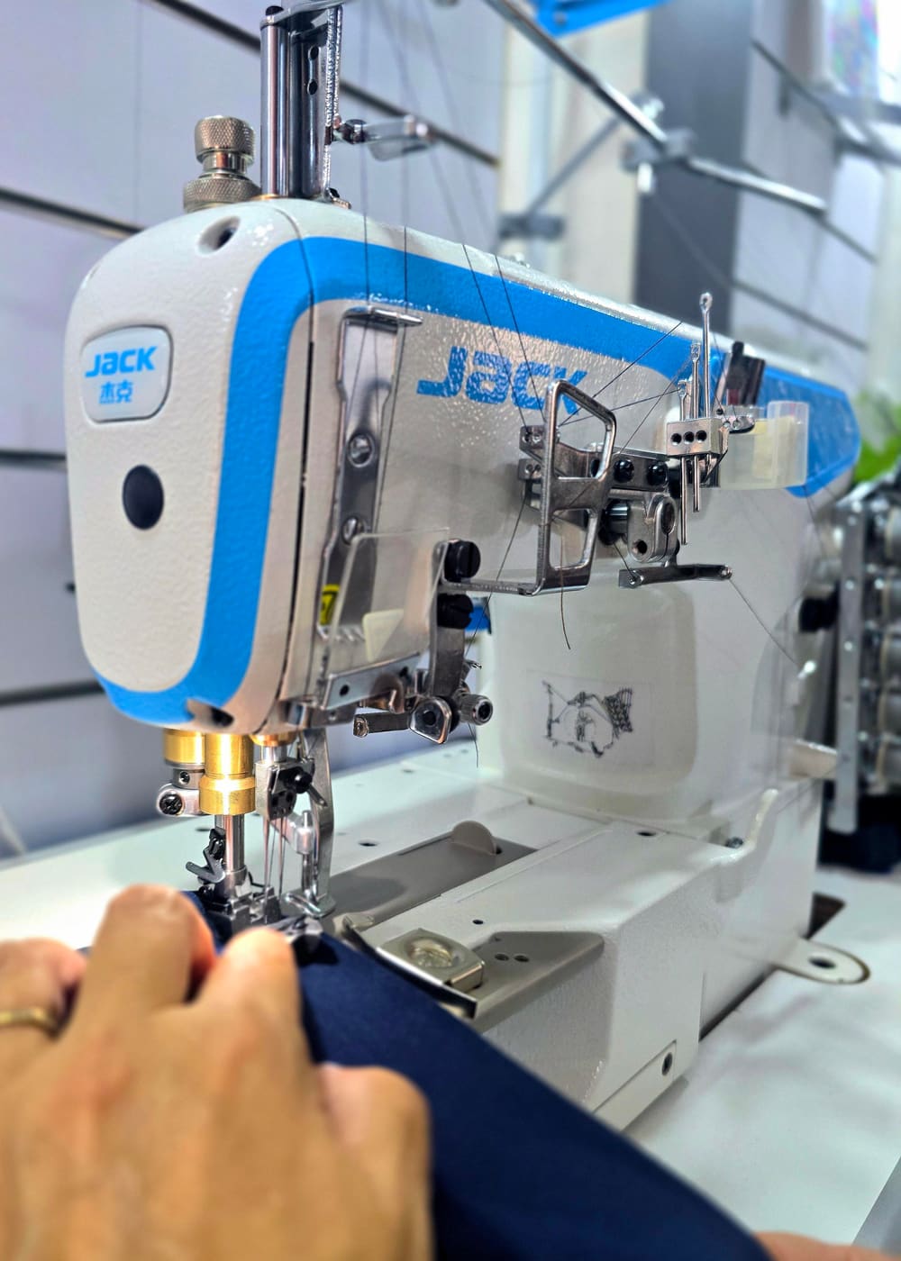 A tailor guiding navy fabric through a sewing machine at Younes Tailor in Blat, Jbeil